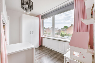 Interior of white room with baby crib and armchair near window in daylight