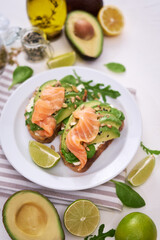 Freshly made Avocado, salmon and cream cheese toasts on a white ceramic plate