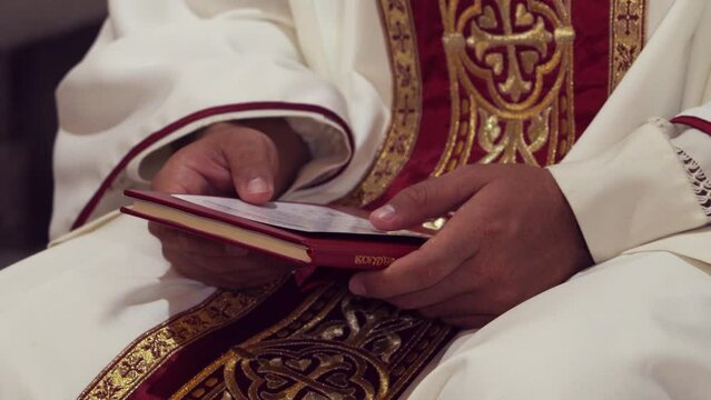 Hombre vestido de sacerdote religioso tomando libro ritual en sus manos sentado meditando orando leyendo 