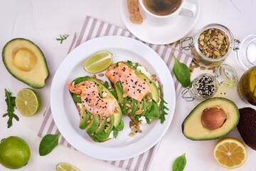 Freshly made Avocado, salmon and cream cheese toasts on a white ceramic plate
