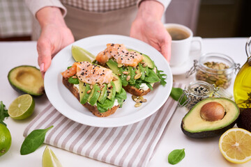 Freshly made Avocado, salmon and cream cheese toasts on a white ceramic plate