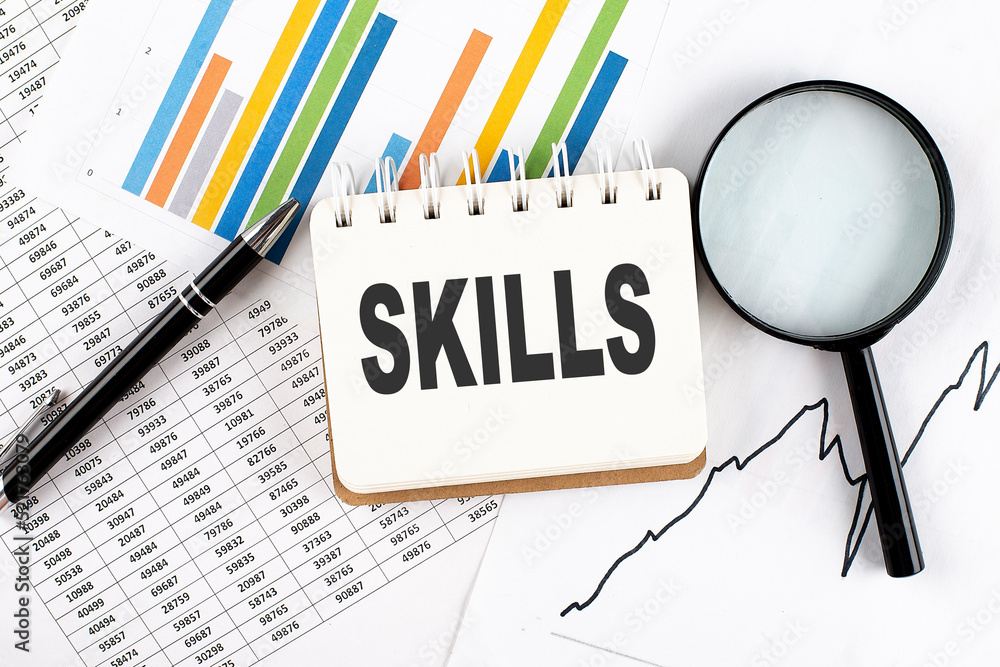 Aufkleber skills text on notebook on the graph background with pen and magnifier