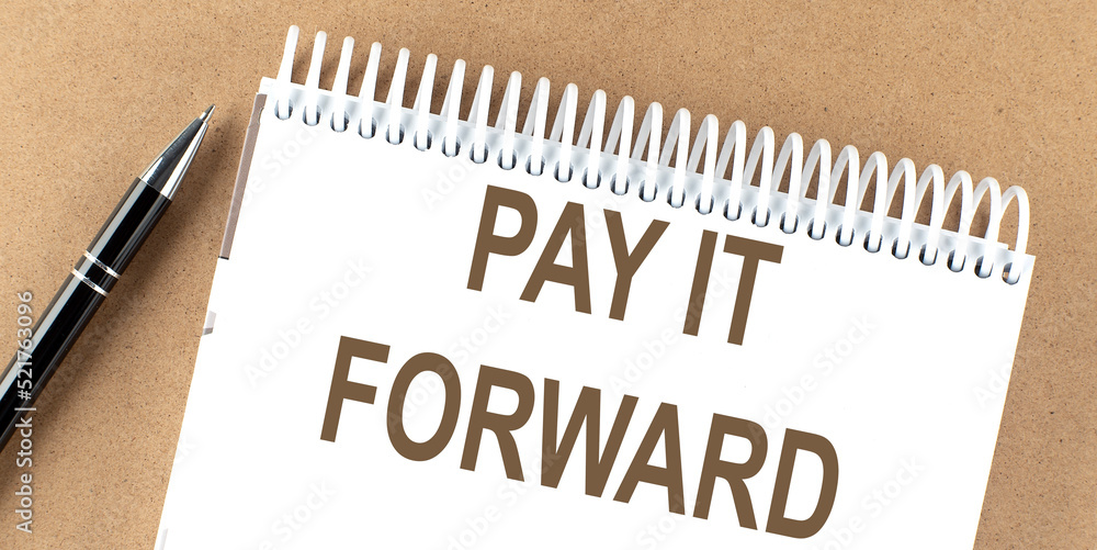 Poster pay it forward text on a notepad with pen, business concept