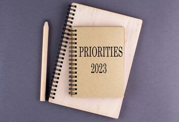 Word PRIORITIES 2023 on notebook with pencil on the grey background