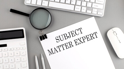 SUBJECT MATTER EXPERT written on paper with office tools and keyboard on the grey background