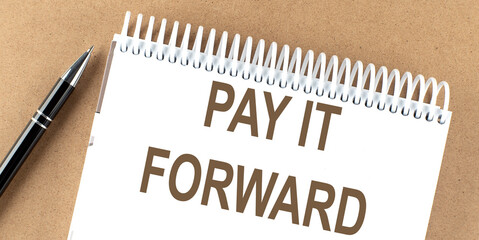 PAY IT FORWARD text on a notepad with pen, business concept
