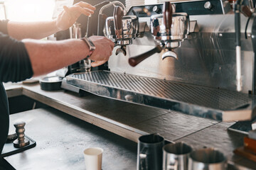 Professional barista warming milk In metal jug with steam of coffee machine