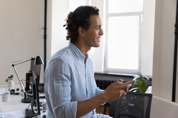 Smiling successful Hispanic businessman, millennial Latin office employee distracted from work use...