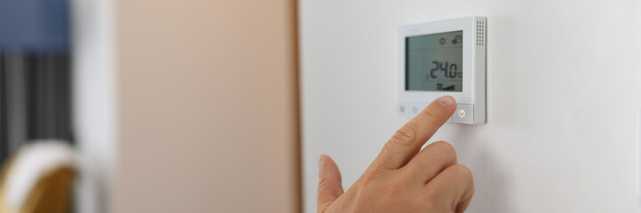 Hand sets a programmable thermostat for heating and cooling - obrazy, fototapety, plakaty