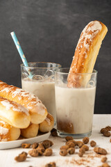 Close-up of glasses with horchata, on a white table with tiger nuts and fartons, gray background, vertical