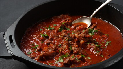 Beef stew with tomato sauce, spices and herbs in a pan