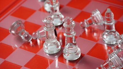 Transparent chess figures, on starting position, on reflective chess board, red tone. Strategic Chess board game