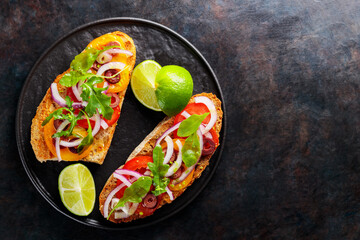 Vegetarian sandwiches on a dark background. Spanish tapas with vegetables, greens, olives and lime. Healthy sandwiches on a black plate. Top view. Copy space
