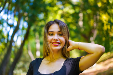 Portrait of a young brunette woman in nature in the natural park in autumn, freedom, smiling