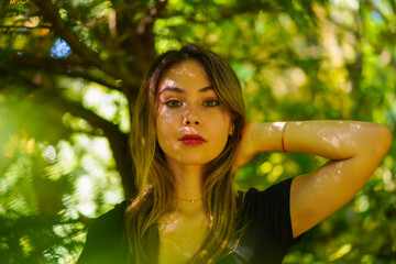 Portrait of a young brunette woman in nature in the natural park, freedom, in the shade of a tree