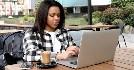 Young african woman using laptop outdoors.