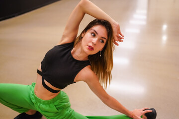 Portrait of a female urban hip-hop dancer inside a building, stretching exercises