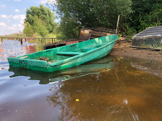 Obraz premium An old abandoned sunken river boat stands on the sandy bank of the river.