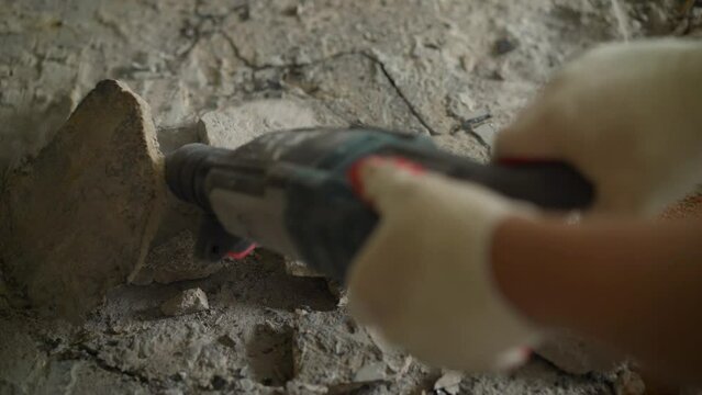 Concrete rubble at the construction site of a house. Destruction of old tiles. The builder breaks the old concrete floor to make a new one. Removing a concrete floor with a hand hammer.