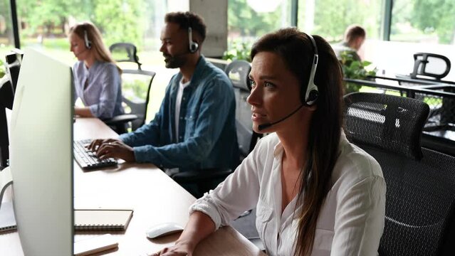 Young woman customer care support service agent call center operator in wireless headset talk consult online client using computer solving complaints on helpline or sell services in telesales office