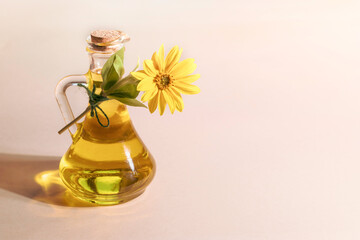 Bottle of sunflower oil and sunflower flowers on a beige background.Space for text