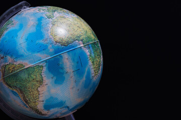 World globe set against a dark black board background. Concept image with copy space available.