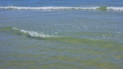 The waves of the ocean are hitting the beach.