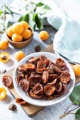 Dried fruits or candied fruit. Dried apricots and raw apricots on a gray stone background.