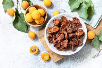 Dried fruits or candied fruit. Dried apricots and raw apricots on a gray stone background. View...