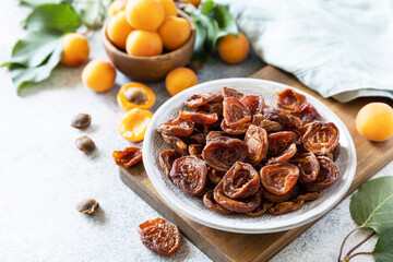 Dried fruits. Dried apricots and raw apricots on a gray stone background.