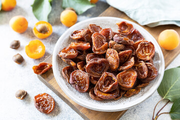 Dried fruits. Dried apricots and raw apricots on a gray stone background.