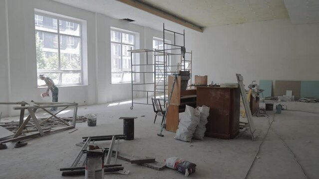 repair and construction work in a large room. A large office space with large windows where the room is being renovated.