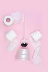 toilet brush and three rolls of toilet paper on a pink background