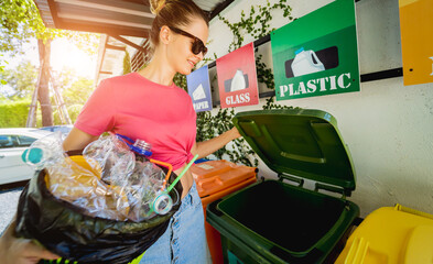 A young beautiful girl throws sorted garbage into special bins