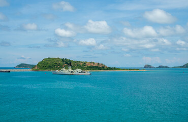 Military warships are stationary beside a small island. against a background of green mountains and...