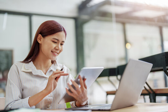 Portrait of an Asian female employee using a tablet computer at work.