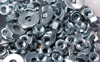 Metal nuts and washers for bolts isolated on white. Nuts for bolts close-up. Metal objects in...