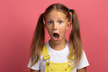 Caucasian girl child in yellow clothes waist-length portrait on a pink background