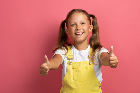 Caucasian girl child in yellow clothes waist-length portrait on a pink background