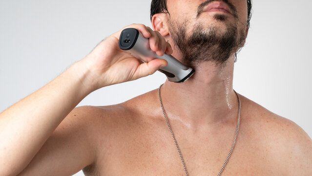 A man shaves his beard with a styler trimmer - self-care at home
