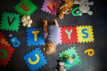 bird view of colorful kids puzzle mat playground in nursery or at home with the letters TOYS on it...