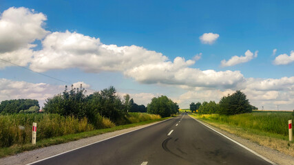 Asphalt road at the summer time. Blue sky with clouds. Travel and transportation concept background
