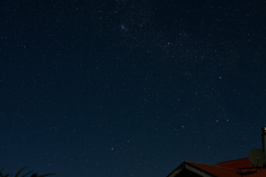 Milky way galaxy with stars and space dust in the universe above a red roof. Southern Hemisphere. Southern Cross constellation and open cluster Collinder 241