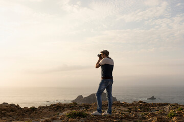 Travel content creator photographer taking pictures of beautiful sea sunset scenery from cliffs for blog, social media. lifestyle freelance photographer concept adventure summer travel outdoors