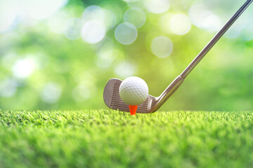 Collection of golf equipment resting on green grass. Blurred golf club and golf ball close up in grass field with sunset.