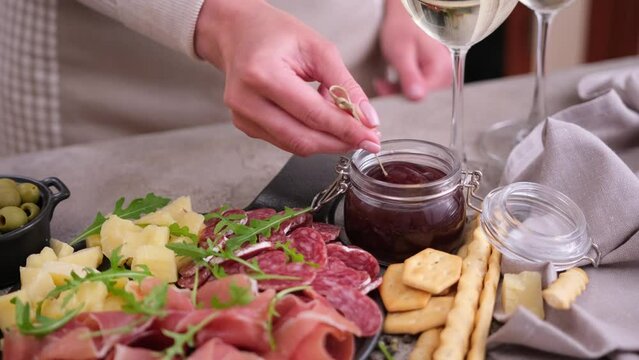 meat and cheese plater at domestic kitchen - woman dips cheese into sauce