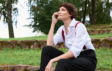 Image of a stylish beautiful woman in a white shirt, black trousers and red suspenders. The concept of style and fashion.