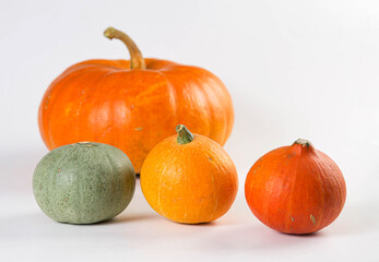 One big pumpkin and three small pumpkins isolated on white background.