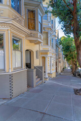 Row of houses near the concrete side walk along the columnar trees at San Francisco, CA
