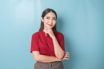 Portrait of a thoughtful young casual girl wearing a red t-shirt looking aside isolated over blue background